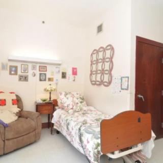 A cozy bedroom with a hospital bed, decorated walls, and a comfortable chair.
