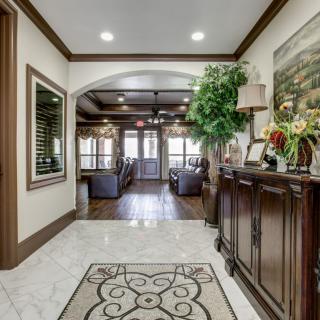 A beautifully decorated hallway with elegant furniture, artwork, and lush greenery.