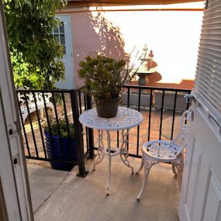 A cozy balcony setting with a white table and chair, adorned with a potted plant, inviting moments of relaxation outdoors.