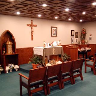 A serene interior of a chapel featuring an altar, wooden benches, and religious decor.