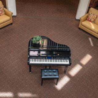 A grand piano situated in a cozy living room with comfortable seating.