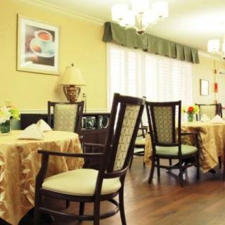 A cozy dining area with elegantly set tables and comfortable chairs, featuring warm lighting and tasteful decor.