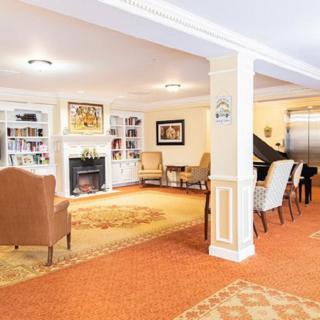 A cozy living room with a fireplace, bookshelves, and a piano.
