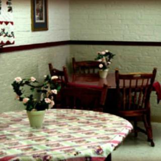 An empty restaurant interior with tables and chairs, decorated with potted plants.