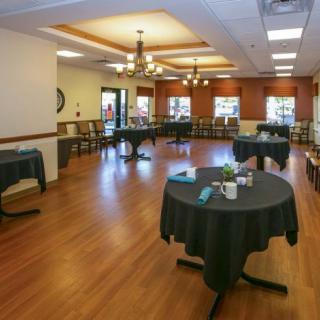 An empty dining area with round tables and wooden flooring.