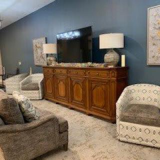 A cozy living room setup with a television on a wooden cabinet, flanked by lamps and surrounded by comfortable seating.