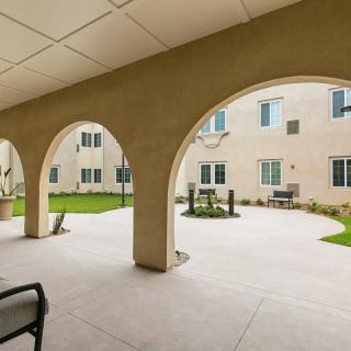 A view of a spacious courtyard with arches overlooking a building exterior.