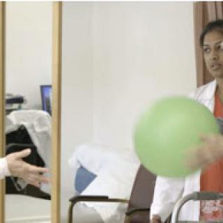 A healthcare professional engages a patient in a therapy session using a green exercise ball.
