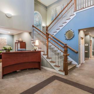 A spacious lobby with a reception desk and a staircase leading to the upper level.