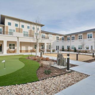 A modern residential building with a landscaped courtyard featuring a small putting green.