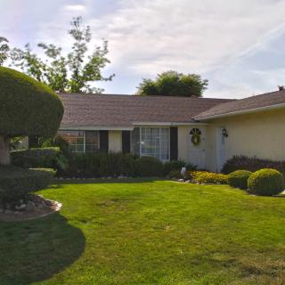 A suburban house with a well-maintained lawn and neatly trimmed bushes.