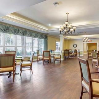 A spacious dining area with elegant chandeliers, wooden flooring, and large windows allowing natural light.