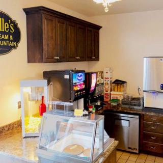 A cozy ice cream shop interior featuring a beverage dispenser and popcorn machine.