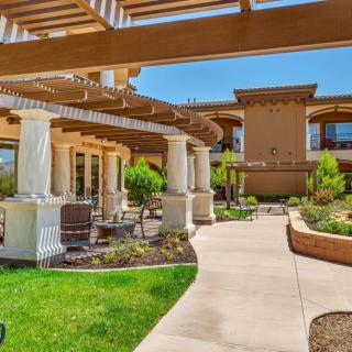 A modern building surrounded by well-maintained gardens and a walkway under a pergola.