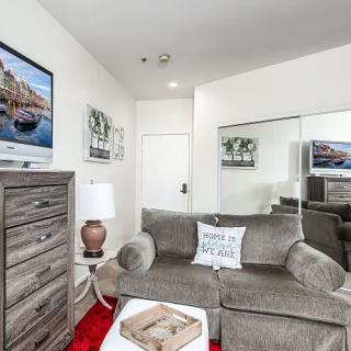 A cozy living room with a sofa, wall-mounted TV, decorative wall art, and a large mirror.