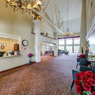 A spacious lobby area featuring chandeliers, a reception desk, and comfortable seating.