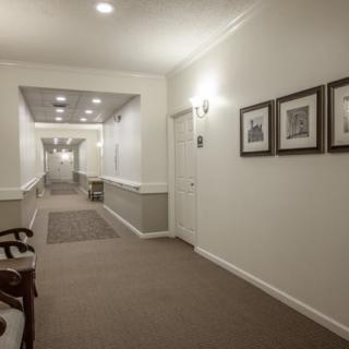 A well-lit hallway with framed pictures on the walls and a carpeted floor.