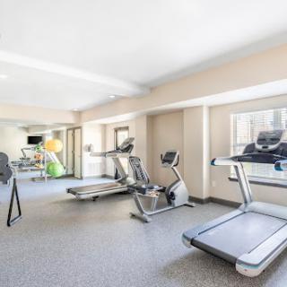 A spacious and well-lit gym area equipped with various exercise machines.