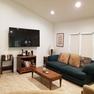 A cozy living room with a sofa, coffee table, and wall-mounted TV.