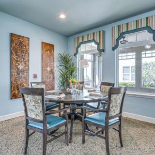 A stylish dining room with a round table set for four, featuring elegant decor and large windows.