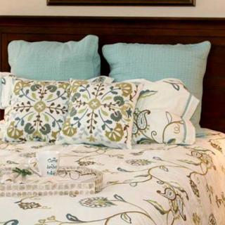 A cozy bed with floral patterned bedding and decorative pillows.