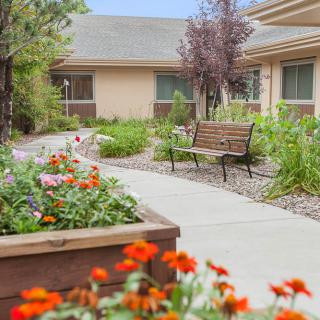 A peaceful garden with a walkway, bench, and vibrant flowers.