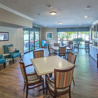 A modern lounge area with dining tables and chairs, featuring large windows and stylish decor.