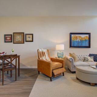 A cozy, modern living room featuring an armchair, sofa, and dining table with art on the walls.