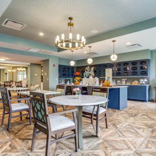 A stylish dining area with elegant furnishings and a chandelier, featuring blue cabinets and wooden flooring.