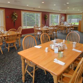 A cozy dining room with wooden tables and chairs, ready for guests.