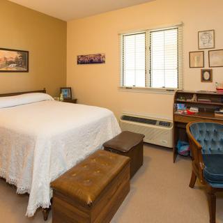 A cozy bedroom with a bed, window, and wooden furniture.