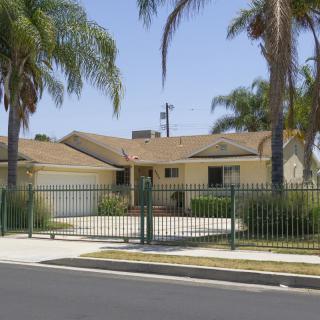 A suburban house with palm trees and a gated driveway.