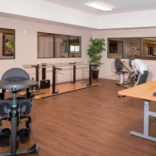 An interior view of a rehabilitation gym equipped with various exercise machines and weights.
