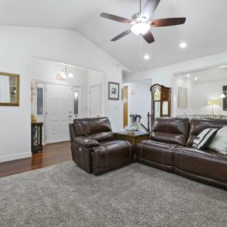 A modern living room featuring a leather sectional sofa, ceiling fan, and elegant decor.