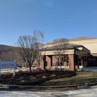 A well-maintained commercial building with landscaping, set against a clear blue sky.