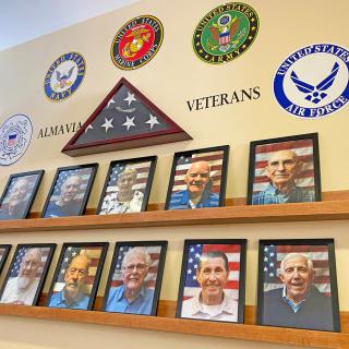 A wall display honoring military veterans with photographs and service branch emblems.