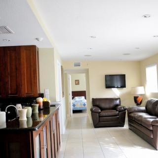 A modern open space living room and kitchen area with a view into a bedroom.