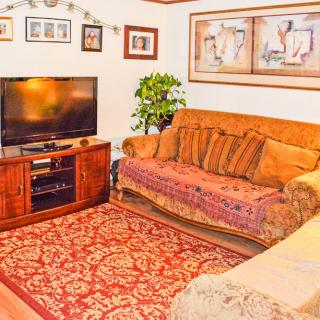 A cozy living room with a sofa, television, and decorative artwork.