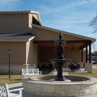 A scenic outdoor area with a fountain in front of a building.