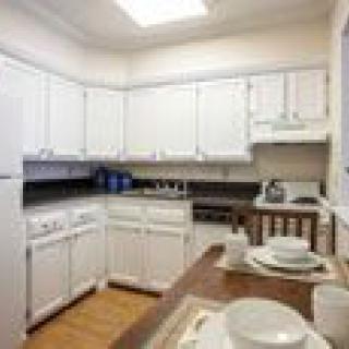 A bright kitchen with white cabinets and a dining area.