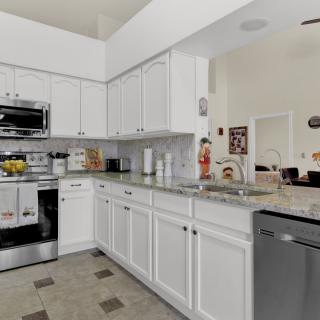 A modern kitchen with white cabinets and stainless steel appliances.