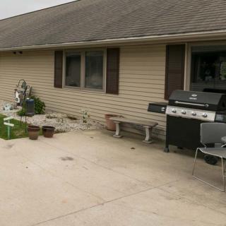 A backyard patio area with a grill, outdoor furniture, and some plants.