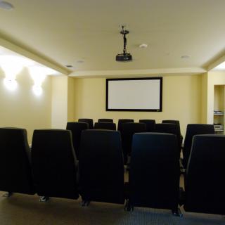An empty home theater room with rows of seats and a projection screen.