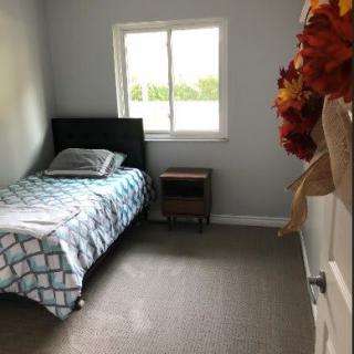 A small bedroom with a single bed, a nightstand, and fall-themed door decor.