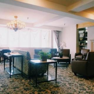 A cozy living room with elegant furnishings, including sofas, a chandelier, and ample natural light.