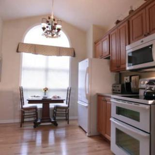 A cozy kitchen with wooden cabinets, modern appliances, and a small dining area with a chandelier.