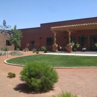 A desert home with a terracotta exterior, featuring a well-maintained lawn and patio.