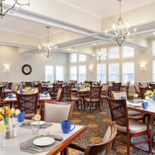 A spacious dining room with elegantly set tables and chandeliers.