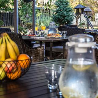 A cozy outdoor dining setting with a fruit basket and a pitcher of lemon water on the table.