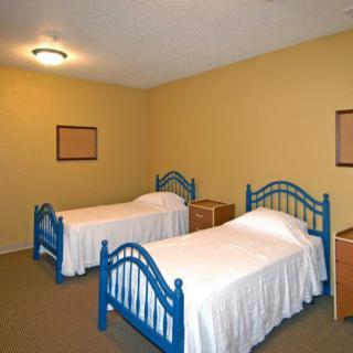 A simple bedroom with two twin beds and minimal decor.